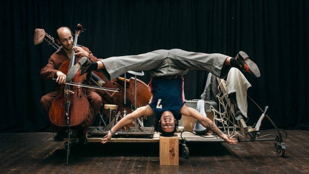 Un uomo a testa in giù con un uomo che suona il violoncello