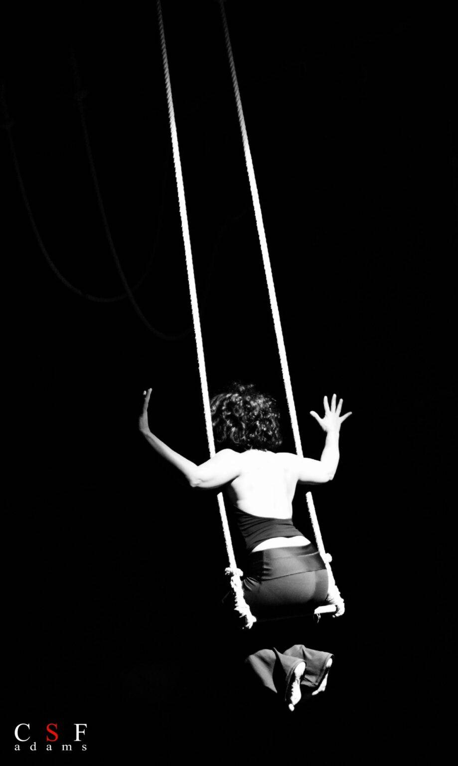 Foto in bianco e nero con performer seduta su un trapezio