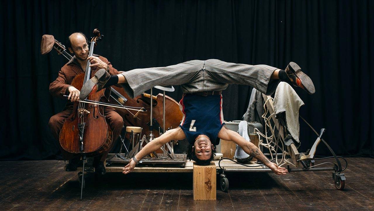 Un uomo a testa in giù con un uomo che suona il violoncello